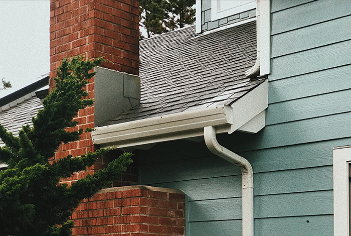 Image of home's gutters and downspout. Inspect and clean your gutters to prevent ice buildup during winter